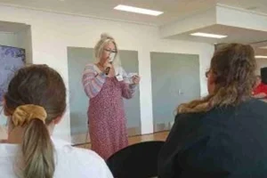 A woman speaking to a room of sitting people