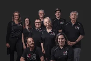 A group of 9 people of different ages and abilities all wearing black tops
