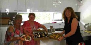 Smiling people in a kitchen with morning tea treats