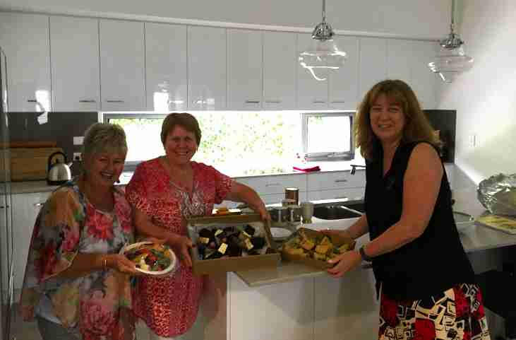 Smiling people in a kitchen with morning tea treats