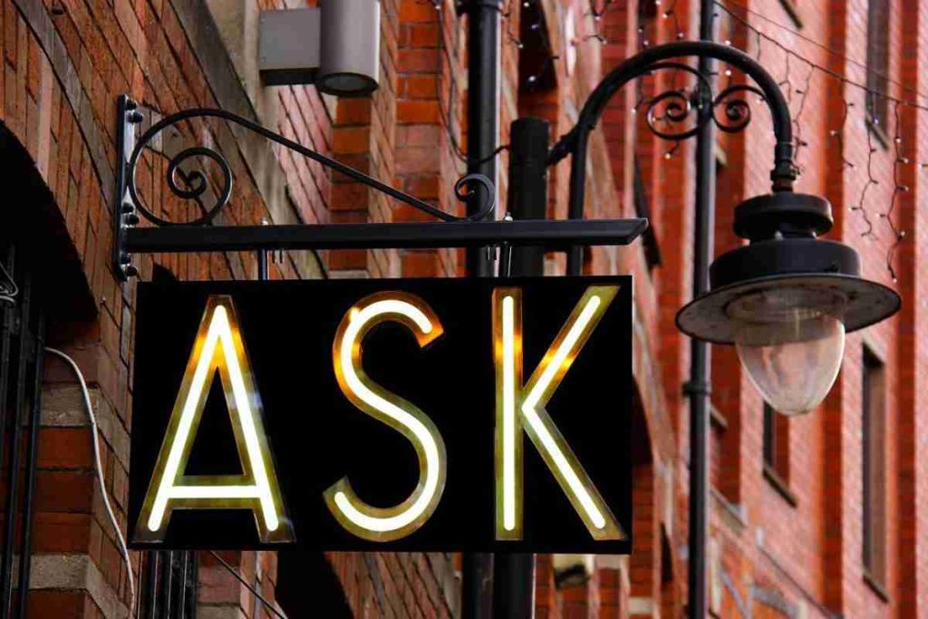 a hanging sign spells ASK in lights