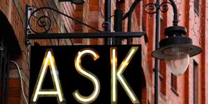 a hanging sign spells ASK in lights