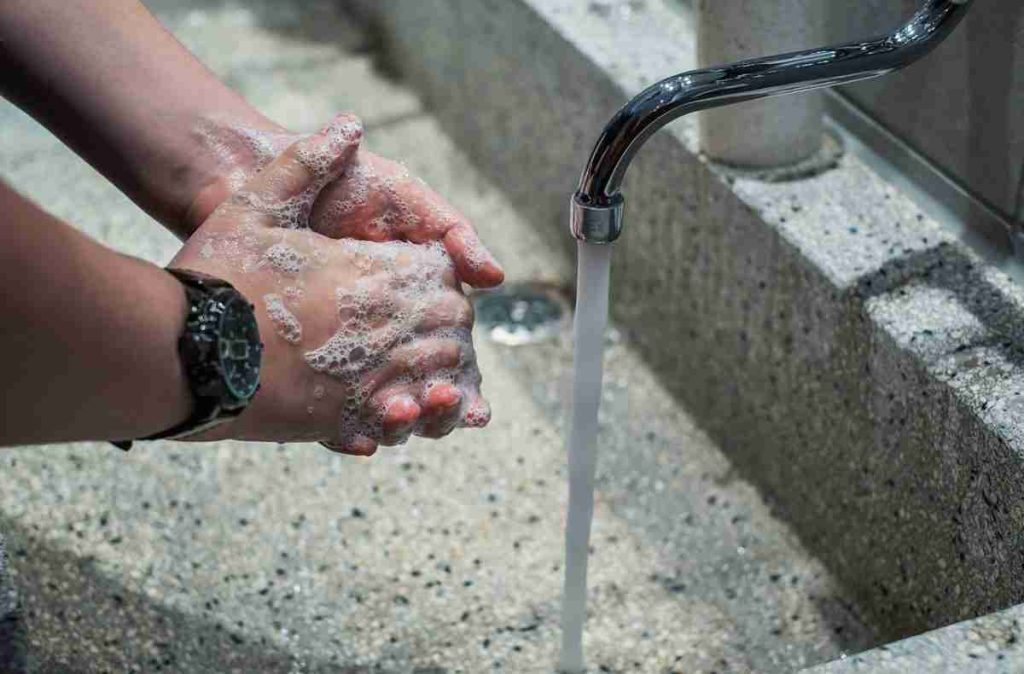 person washing their hands under running tap
