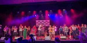 Photo of stage with many people on the stage perfoming with instruments
