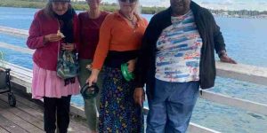 Participants of Taums Fishing day leaning against a railing at the beach