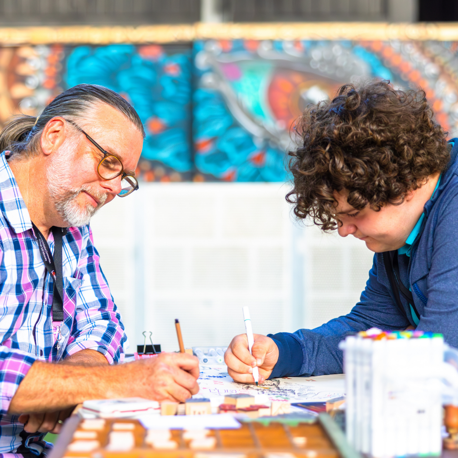 An older man with a young man working together at a table