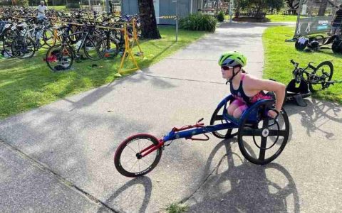 A woman who has an amputation wearing a helmet riding a modified bike