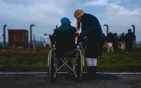 Silhouette of person in wheelchair and person standing next to them