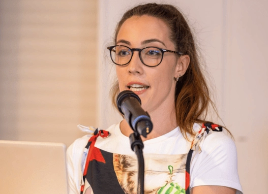 A woman wearing glasses speaking into a microphone