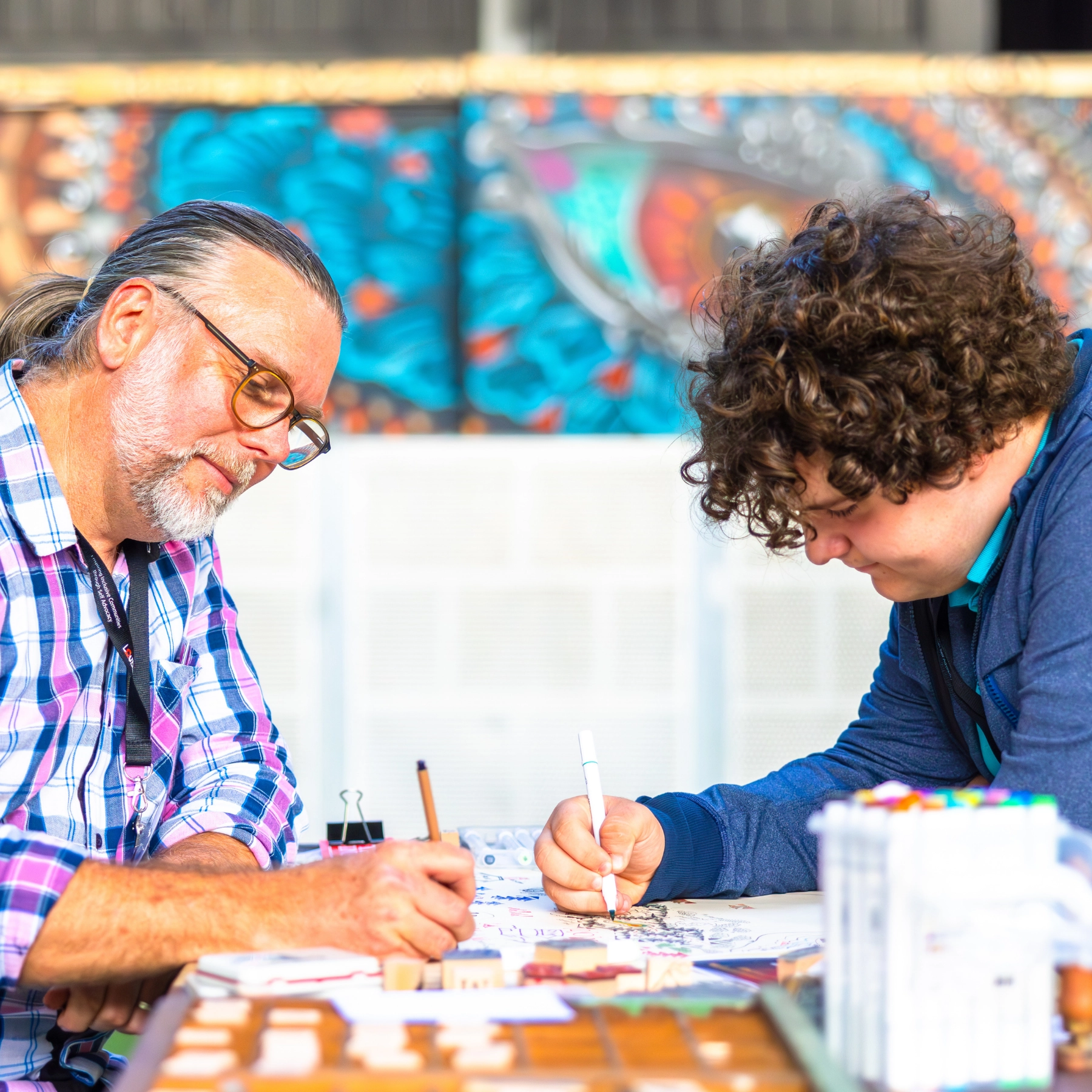 An older man with a young man working together at a table