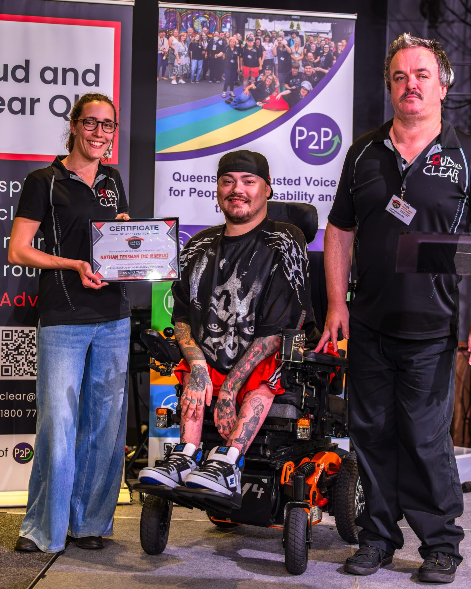 3 people, one in a wheelchair, receiving a certificate